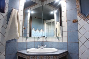 A bathroom with a white sink, a glass mirror, and blue patterned tiles. - Casa Cueva de las Palomas (Los Llanos)