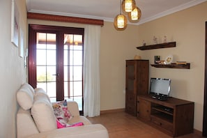 A living room with a sofa, TV stand, and decorative items.
