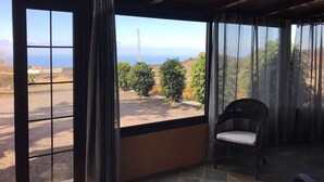 Ein Zimmer mit einem großen Fenster und Meerblick, im Hintergrund ein weiter Strommasten.