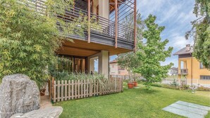 Un edificio residencial con balcón, cerca de madera y césped bien cuidado.