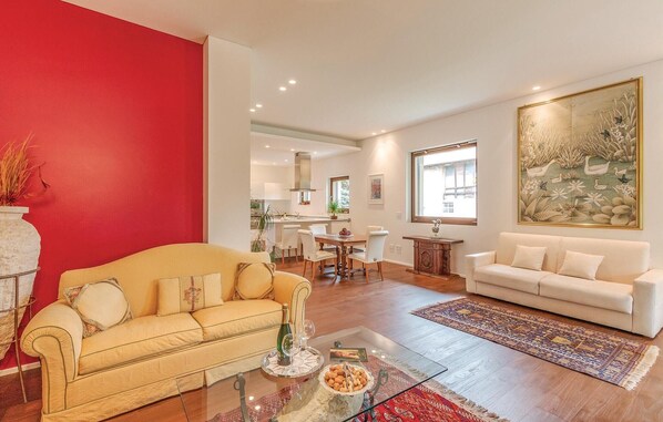 Una sala de estar con un sofá amarillo, un sofá blanco, una mesa de centro de vidrio y una pared de acento roja.