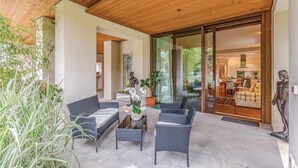 Un área de estar al aire libre con muebles de mimbre, una planta en maceta y una estatua.