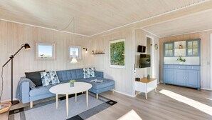 Ett modernt vardagsrum med en blå soffa, ett runt soffbord och ett blått skåp med glasdörrar.