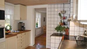 A kitchen with white cabinets, a coffee machine, and a hanging basket with vegetables.