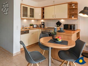 Uma cozinha moderna com uma mesa de jantar redonda, cadeiras pretas e uma fruteira.