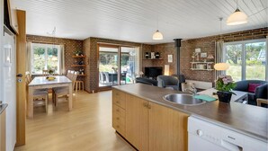 A modern kitchen with a large island, wooden cabinets, and a built-in dishwasher.