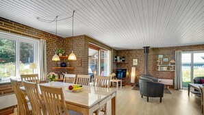 A spacious living area with a dining table, wooden chairs, a sofa, and a fireplace.