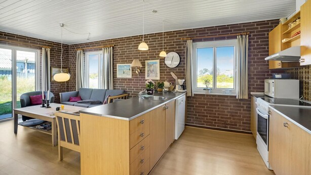A modern kitchen with a central island, wooden cabinets, and a brick accent wall.