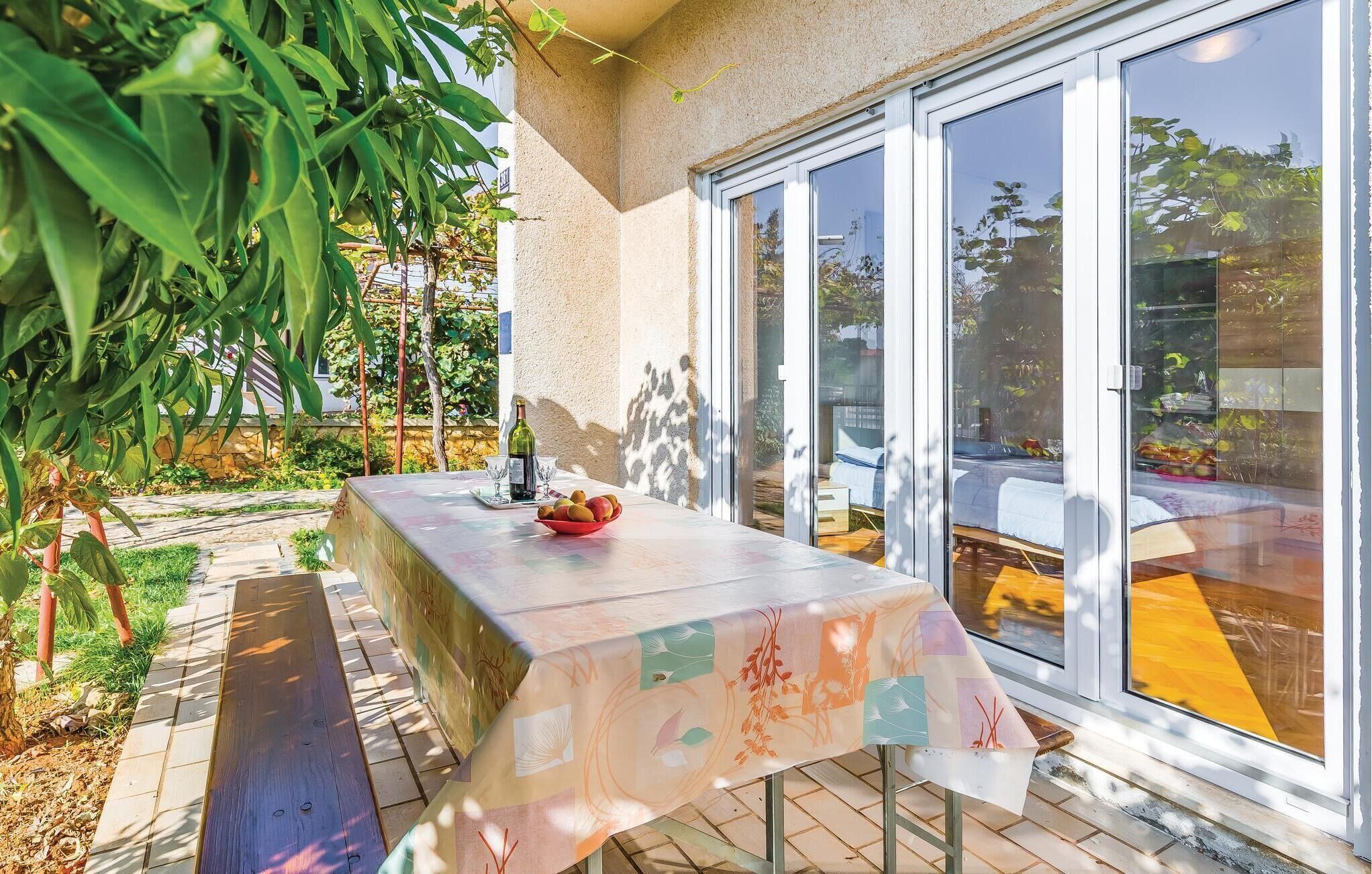 A patio with a table set for two, a bottle of wine, and a bowl of fruit.