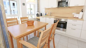 A modern kitchen with white cabinets, a wooden dining table, and chairs.