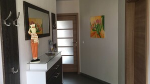 A hallway with a glass-top desk, a wooden door, and two paintings on the walls. - House Lachmöwe Karl Hagen on Usedom - House Lachmöwe (Karlshagen)