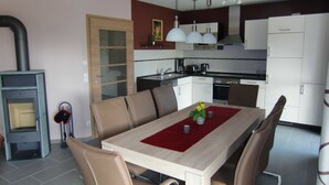 A modern kitchen with white cabinets, a built-in oven, and a dining area with a wooden table and chairs. - House Lachmöwe Karl Hagen on Usedom - House Lachmöwe (Karlshagen)