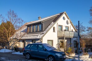 A two-story building with a sloped roof, a balcony on the upper floor, and a parked car in front. - Le Papillon apartment rental - Apartment (Kröslin)