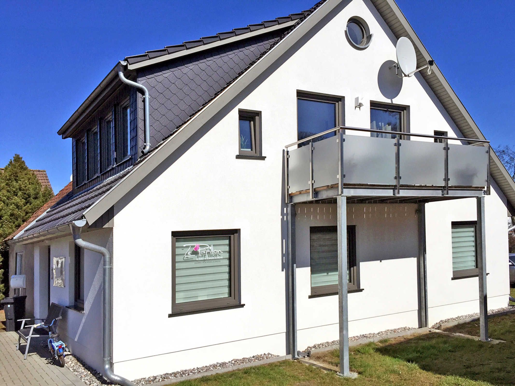 Ein modernes, zweistöckiges Haus mit Balkon, Satellitenschüssel und einem kleinen Fenster mit einem Schild.