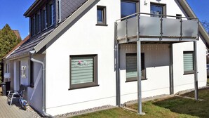 A modern two-story house with a balcony, satellite dish, and a small window with a sign. - Le Papillon apartment rental - Apartment (Kröslin)