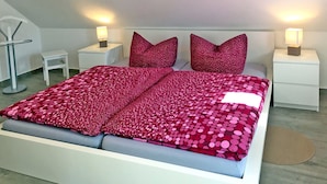 A modern bedroom with a large bed, two nightstands, a small table, and a floor lamp. - Le Papillon apartment rental - Apartment (Kröslin)
