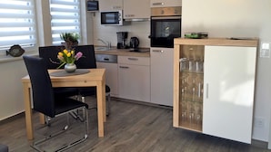 A compact kitchen with a dining area, a microwave, an oven, and a refrigerator. - Le Papillon apartment rental - Apartment (Kröslin)