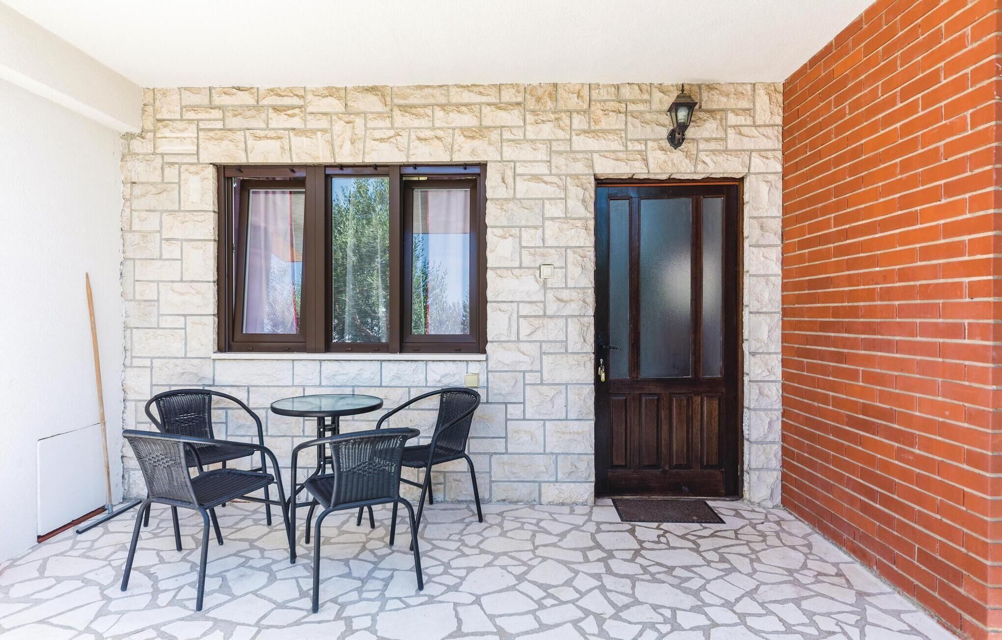 Un petit espace extérieur aménagé avec un sol en pierre, un mur en pierre et une porte en bois.