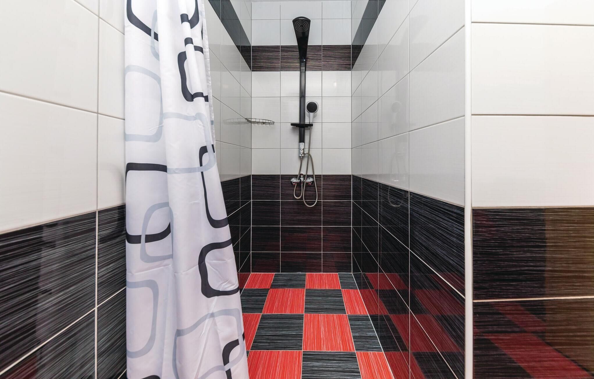 A shower area with a checkered floor, a showerhead, and a curtain.