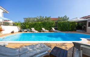 Une piscine avec des chaises longues et une terrasse en bois.
