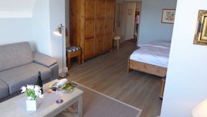 A room with a bed, a sofa, a wooden wardrobe, a table with a bottle and a glass, and a chair. - (129/8) 1- room apartment balcony - apartment house Plückhahn (Kühlungsborn)
