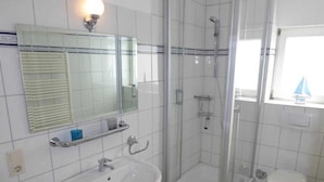 A bathroom with a glass-enclosed shower, a sink, and a toilet. - (129/8) 1- room apartment balcony - apartment house Plückhahn (Kühlungsborn)