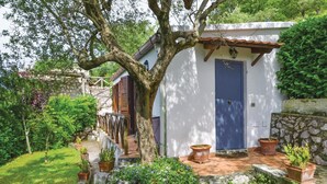 Una casa rústica de exterior blanco, puerta azul y pared de piedra.