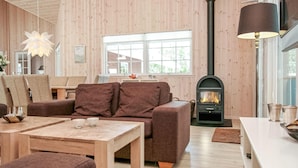 A cozy living room with a sofa, a table, and a fireplace. - Amazing home in Idestrup with sauna (Idestrup)