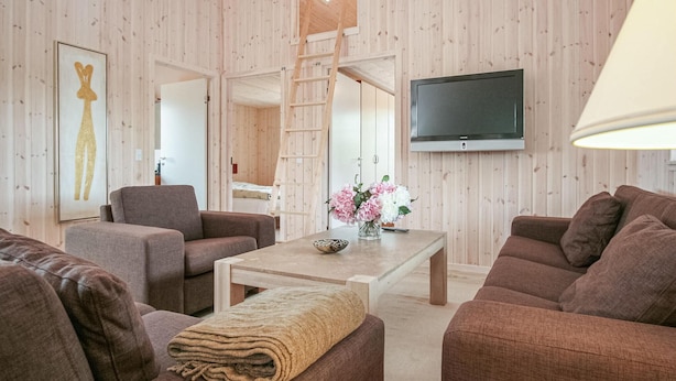 A modern living room with wooden walls, a flat-screen TV, and a sofa set. - Amazing home in Idestrup with sauna (Idestrup)
