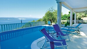 Zona de piscina con sillas de descanso y vistas al mar.