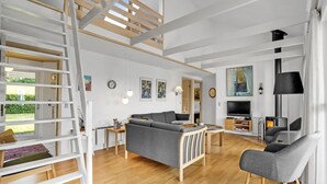 A spacious living area with a sofa, chairs, a TV, and a fireplace.