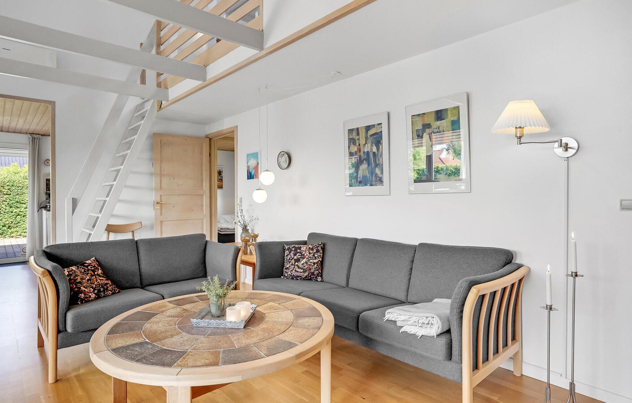 A modern living room with a grey sectional sofa, a round coffee table, and a staircase leading to an upper level.