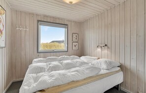 A bedroom with a bed, a window, and wooden walls. - Lovely home in Fanø with WiFi (Fanø)