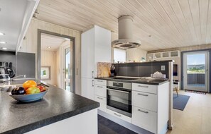 A modern kitchen with a large island, built-in oven, and a view of the outdoors. - Lovely home in Fanø with WiFi (Fanø)