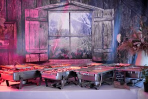 A buffet setup with various food options, a chalkboard menu, and a rustic backdrop.