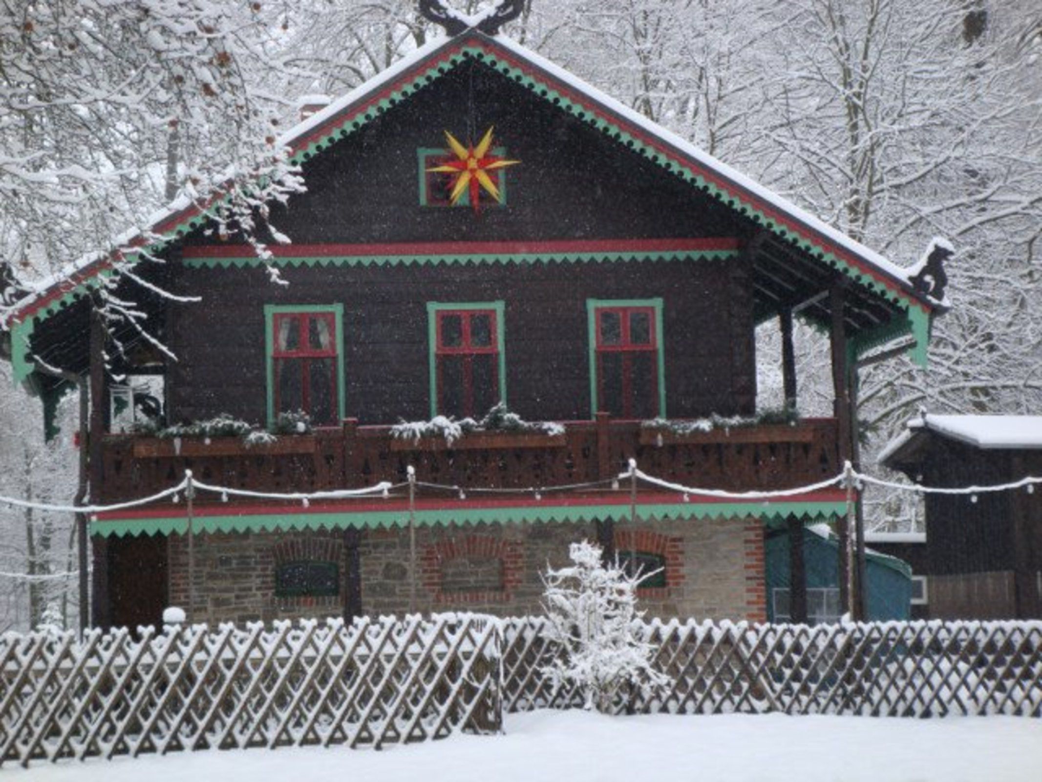 Ein traditionelles Holzhaus mit verschneietem Dach und einer Sternverzierung.