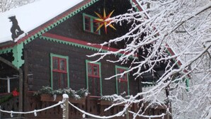 A wooden house with a snow-covered roof and a star decoration.