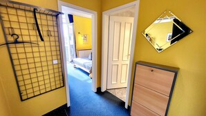 A hallway with a metal rack, a wooden cabinet, and a door leading to a bedroom. - (165) 2-room apartment - apartment house Sonnenresidenz I (Kühlungsborn)