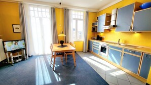 A compact kitchen with a dining area, featuring a TV, a dining table with chairs, and a microwave. - (165) 2-room apartment - apartment house Sonnenresidenz I (Kühlungsborn)