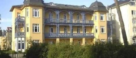 A multi-story building with a yellow facade, balconies, and a dome-shaped roof.