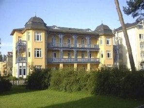 A multi-story building with a yellow facade, balconies, and a dome-shaped roof. - (165) 2-room apartment - apartment house Sonnenresidenz I (Kühlungsborn)