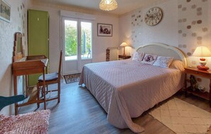 Ein Schlafzimmer mit Bett, Schreibtisch, Stuhl, Lampe und einer Uhr an der Wand.