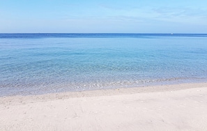 En strand med klart, grunt vatten och en sandstrand.