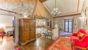A spacious living room with a red armchair, wooden cabinet, and a large rug.
