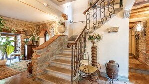 A grand staircase with stone walls and a wrought iron railing, leading to an upper floor.