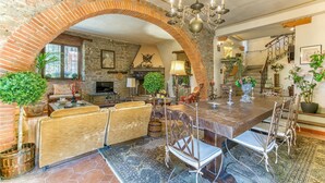 A spacious dining area with a brick archway, a chandelier, and a fireplace.