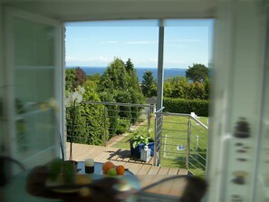 Ein Balkon mit Meerblick, einem Geländer und einem Tisch mit Früchten und einer Kerze.