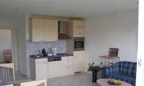 A compact kitchen with a dishwasher, oven, and a dining area with a table and chairs.