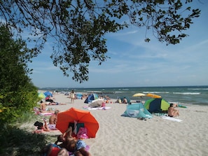 A beach with people sunbathing, umbrellas, and tents.