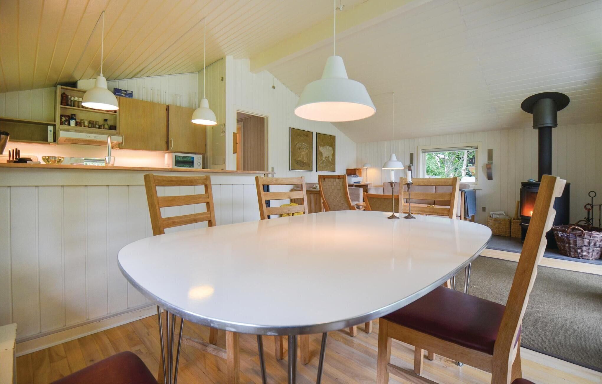 A modern kitchen with wooden cabinets, a white island, and pendant lighting.